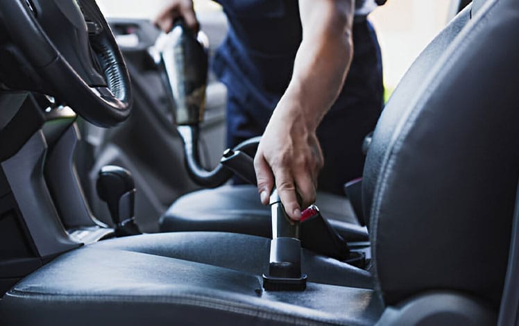 homem passando aspirador no interior do carro