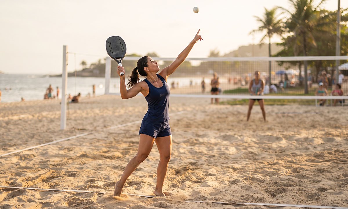 Jogador treinando um lançamento de bola estável antes do saque no Beach Tennis.