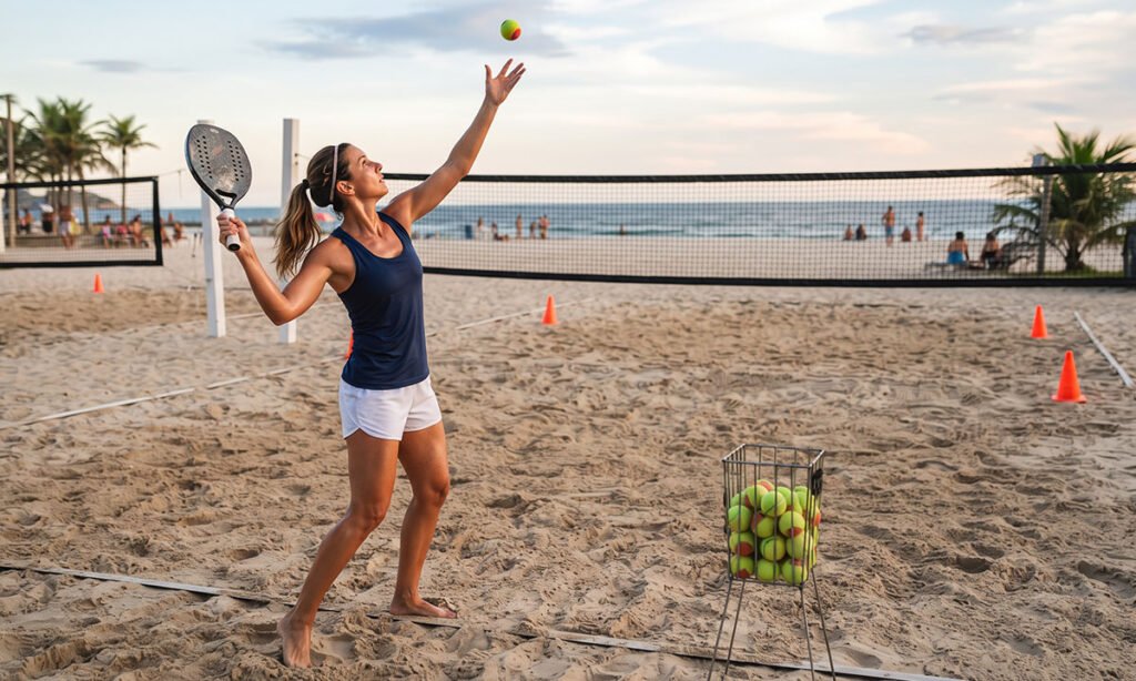 Ponto de contato alto e equilibrado durante um saque de Beach Tennis.